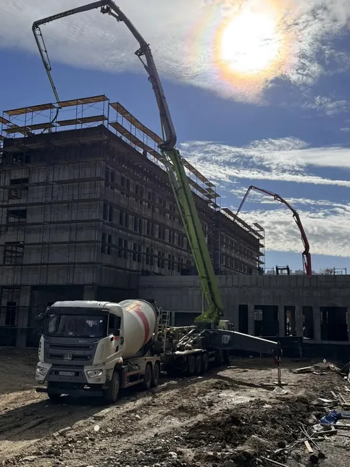 Красный автобетоносмеситель «НеваСтройТорг» под загрузкой на БРУ завода